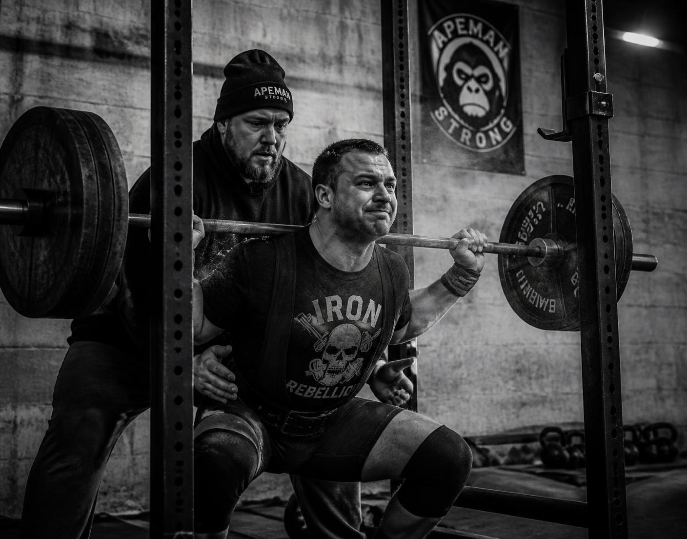 Coach supporting a lifter under a loaded bar